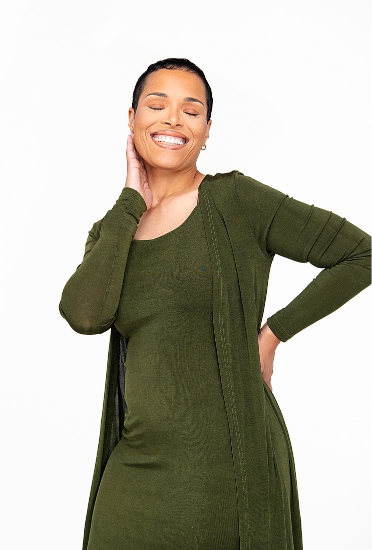 Smiling woman in green outfit, joyful pose.