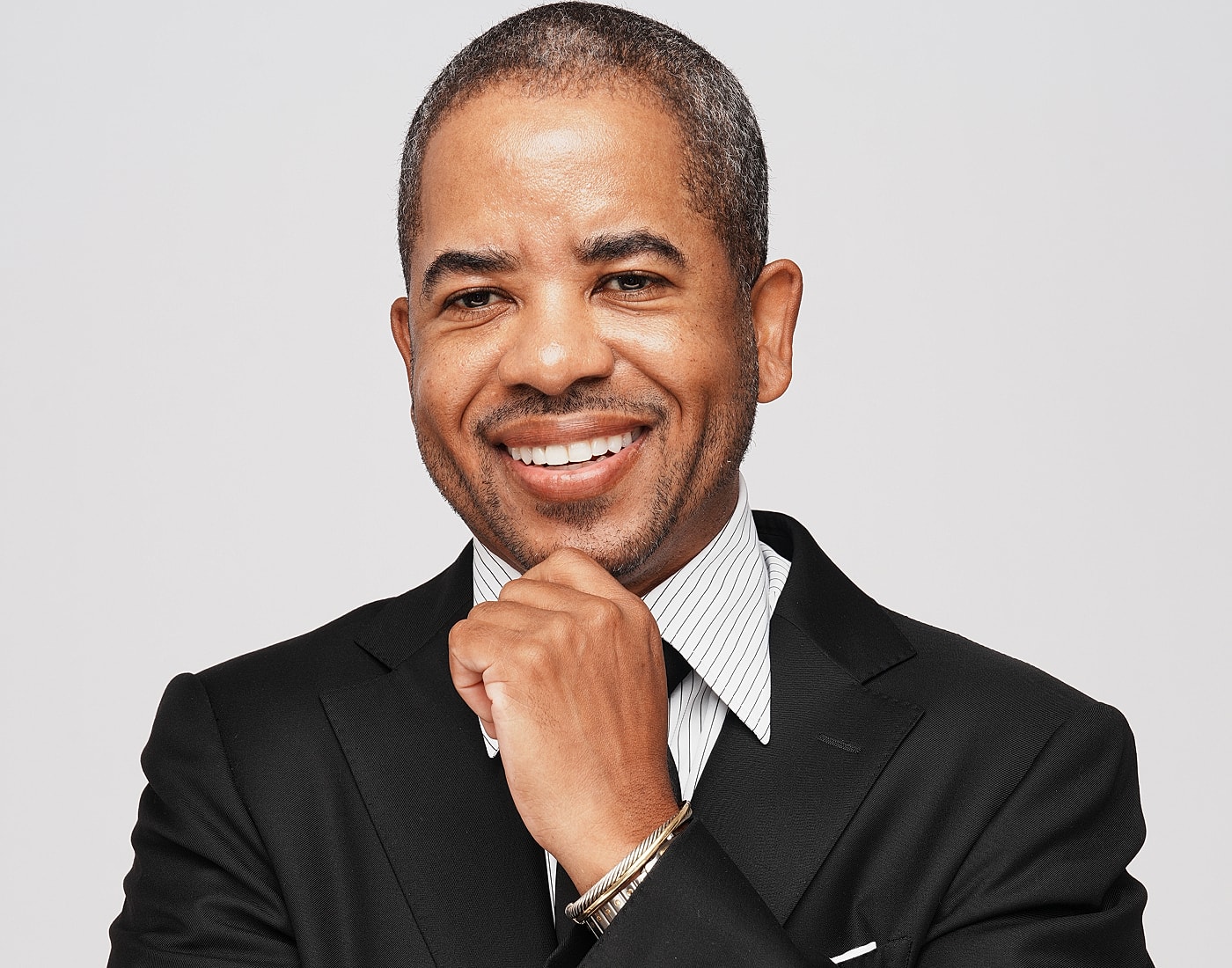 Smiling man in a black suit and tie.